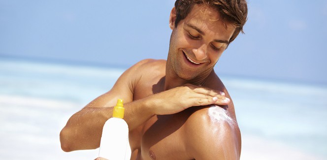 Ein junger Mann trägt Sonnenschutz auf.